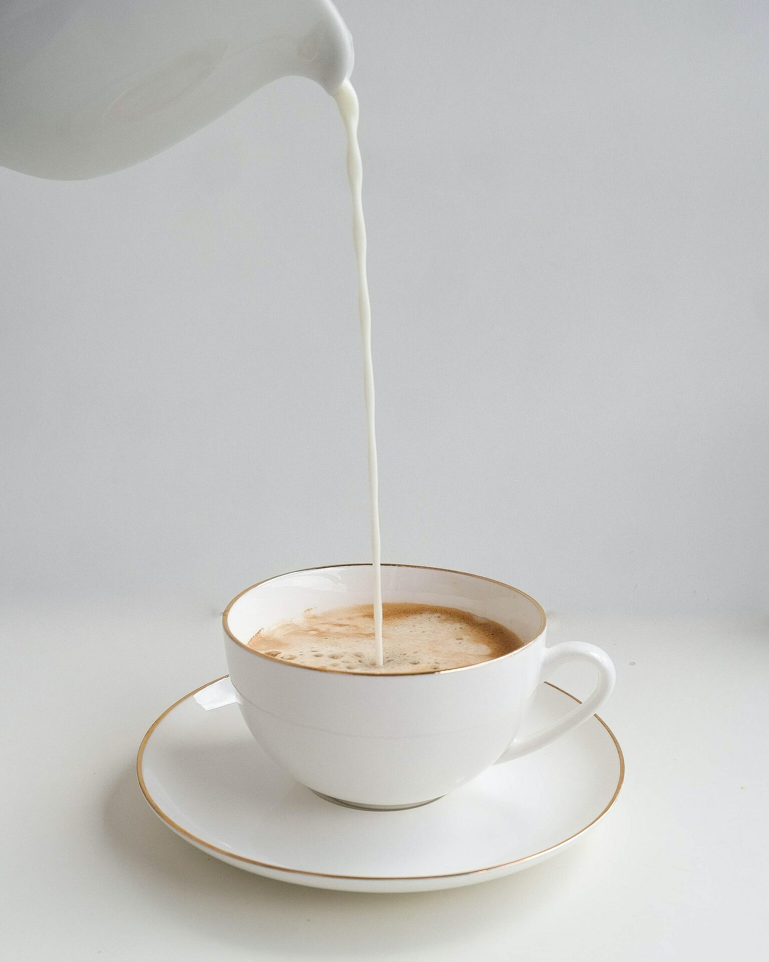 pouring milk into a coffee cup pouring milk into a coffee cup